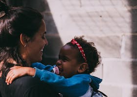 A mother and daughter share a joyful embrace outside, exuding warmth and affection.